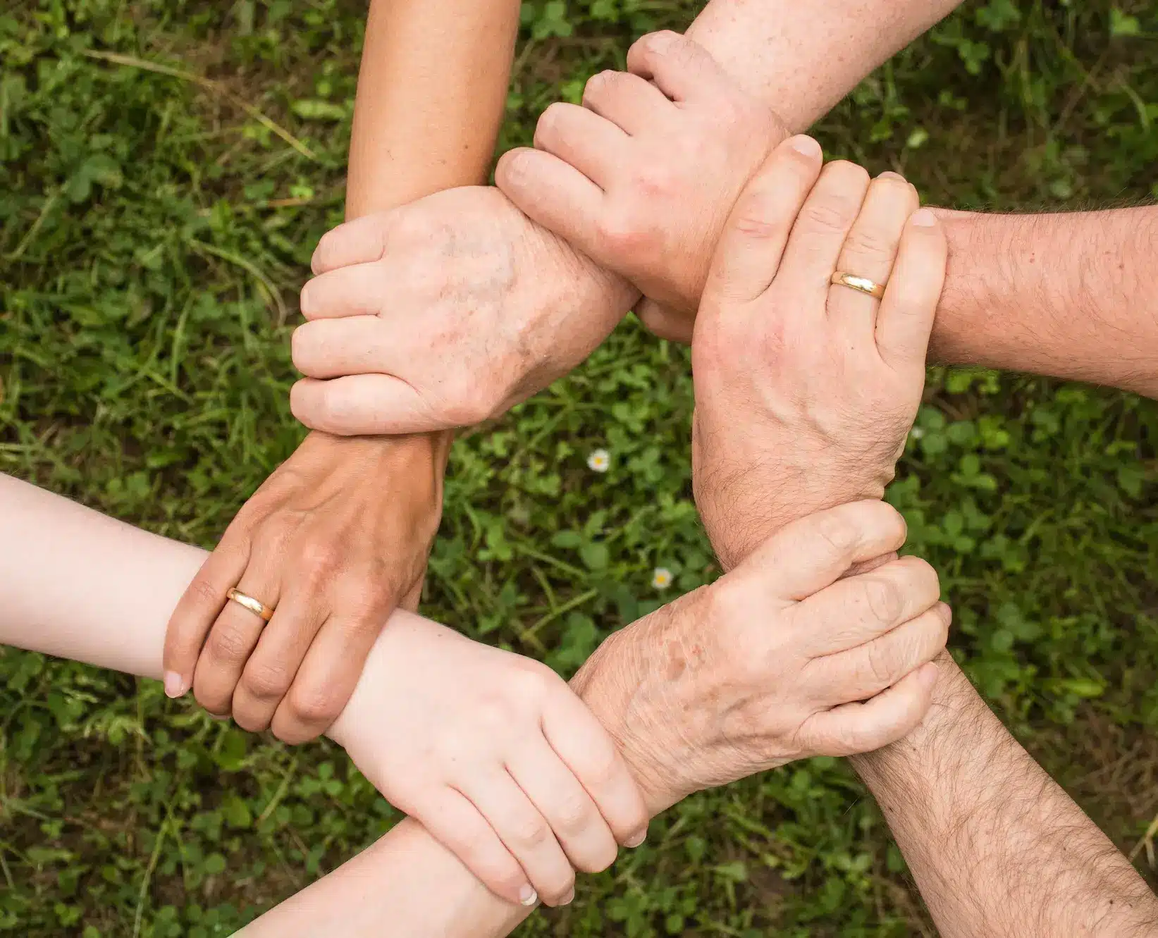 Personnes se tenant les poignets en cercle pour symboliser la solidarité, l'entraide et le lien social